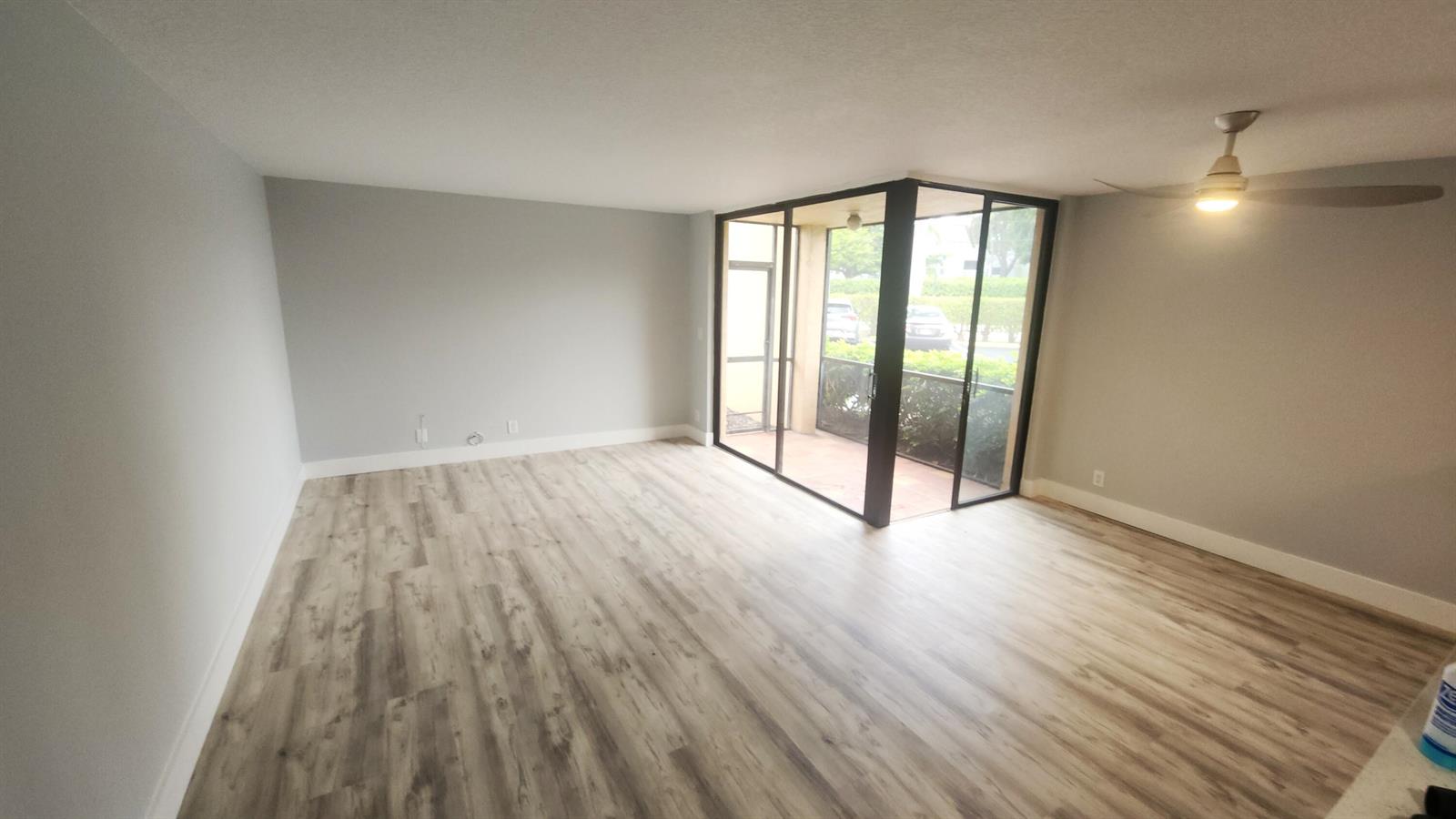 This living room features a neutral sofa, wood coffee table, and glass doors to a balcony — 2255 Lindell Boulevard # 4111, Delray Beach FL 33444, DELRAY BEACH, FL