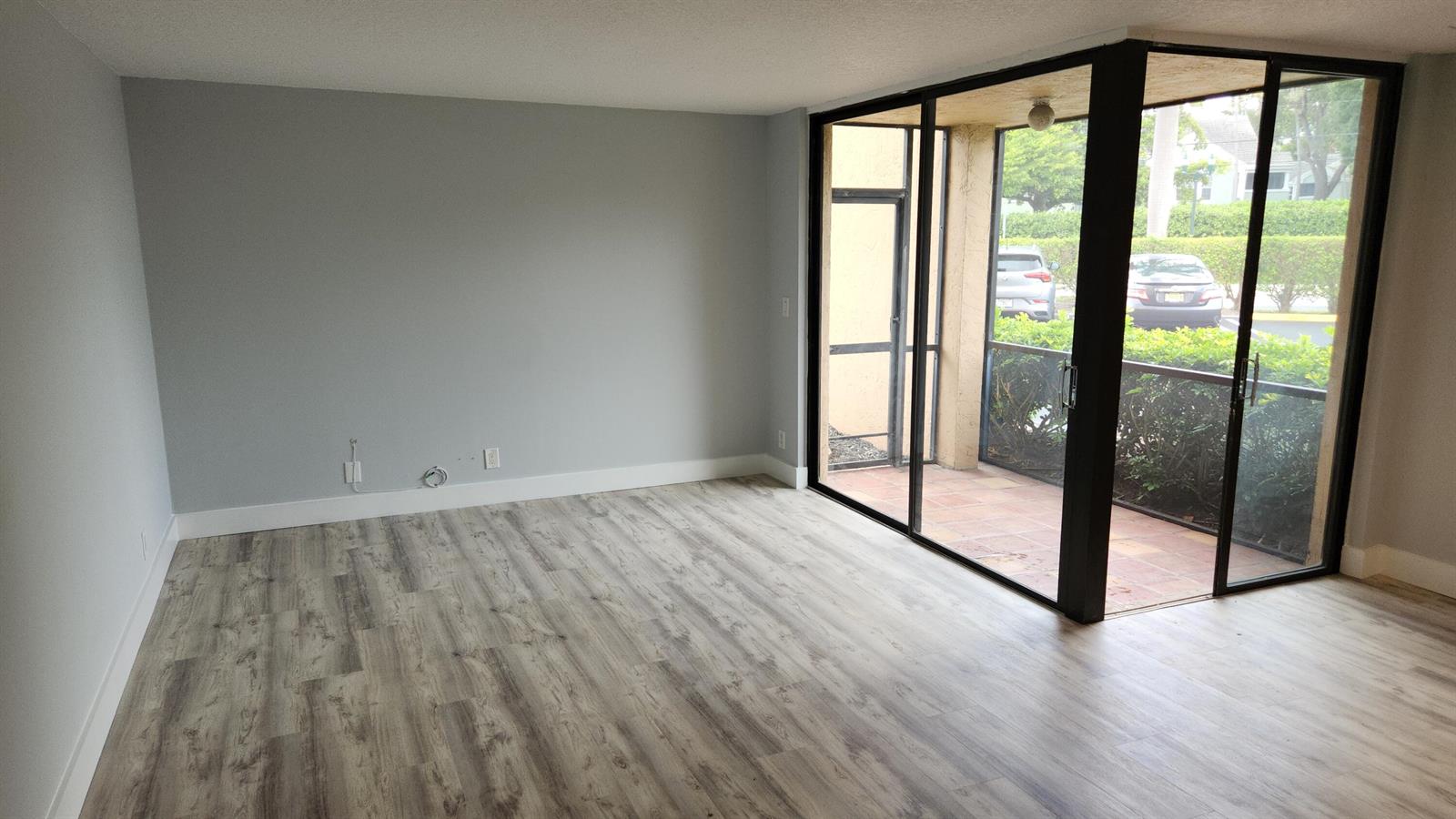 A screened-in patio with terracotta tile flooring overlooks a parking lot and green hedges — 2255 Lindell Boulevard # 4111, Delray Beach FL 33444, DELRAY BEACH, FL