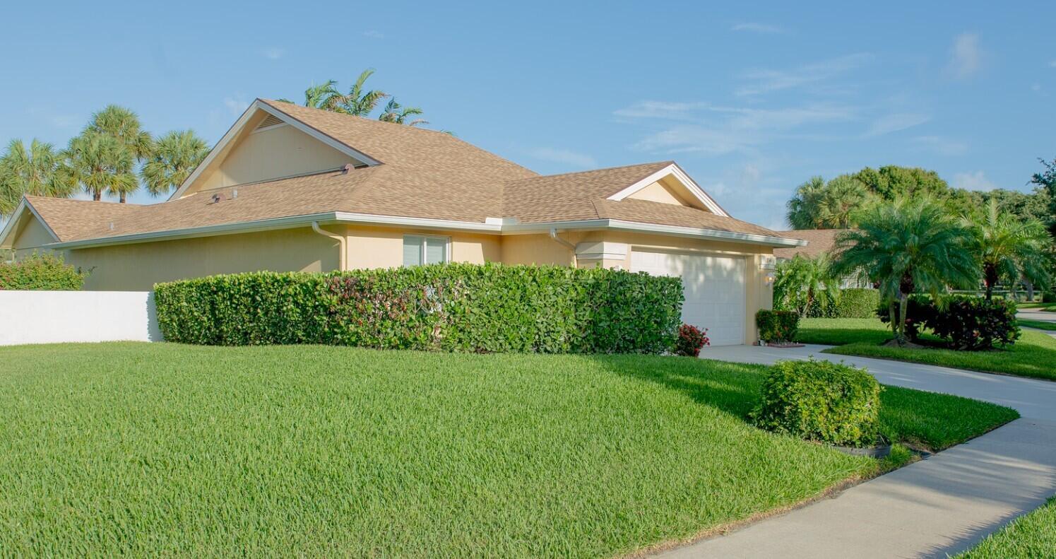 A single-story house with a tan exterior, brown shingled roof, and a manicured hedge — 114 Beach Summit Court, Jupiter FL 33477, JUPITER, FL