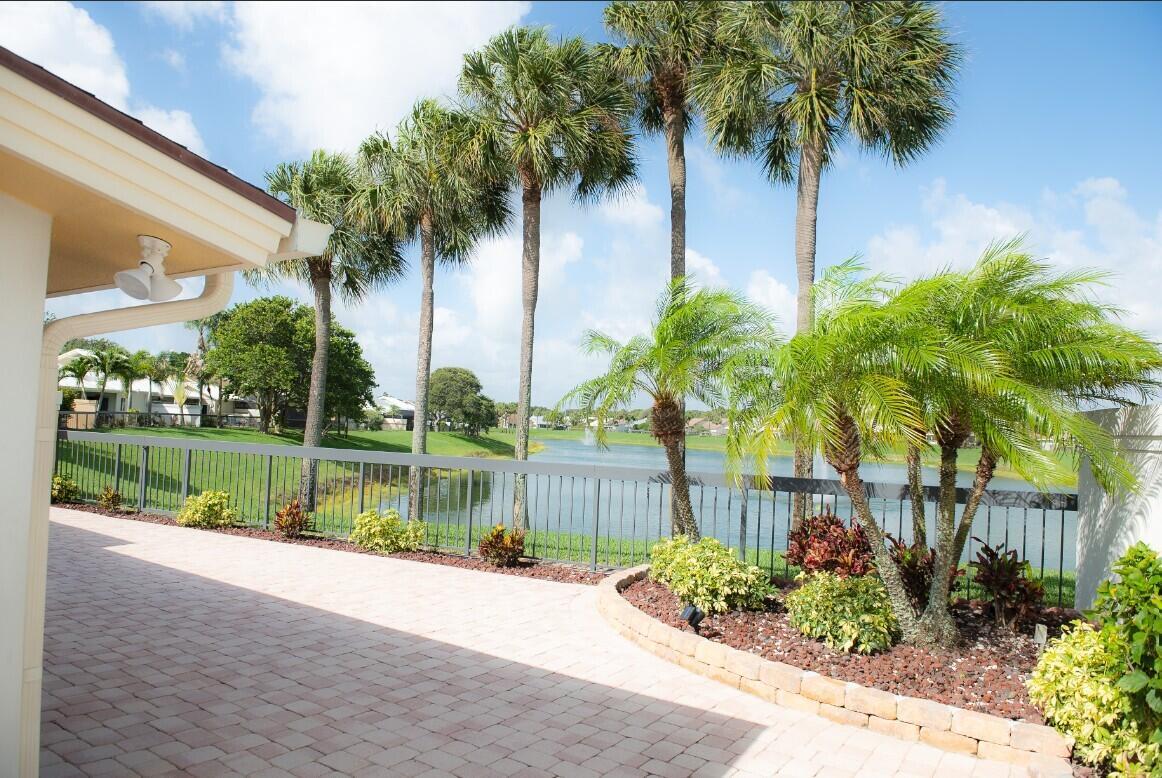 A paved patio overlooks a lake with palm trees and a metal fence — 114 Beach Summit Court, Jupiter FL 33477, JUPITER, FL
