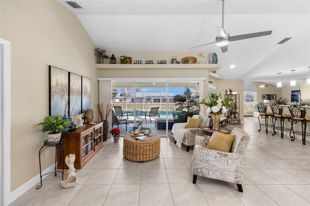 A living room with tile floors, a wicker coffee table, and sliding doors to a pool — 26549 VALPARAISO DRIVE, PUNTA GORDA, FL