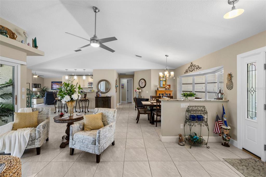 A bright, open-concept living and dining area features tiled floors, vaulted ceilings, and neutral walls — 26549 VALPARAISO DRIVE, PUNTA GORDA, FL