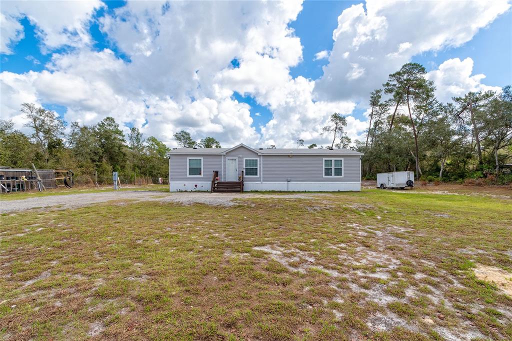 A single-story manufactured home with light gray siding sits on a large, grassy lot — 42300 FONSECA LANE, DELAND, FL