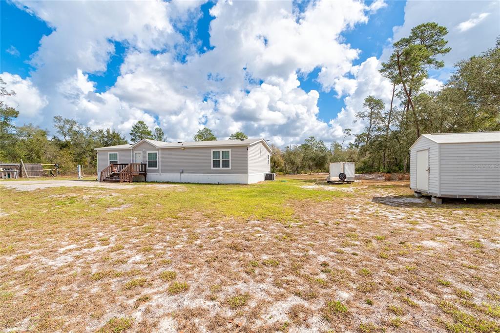 A light gray manufactured home sits on a large, grassy lot with a storage shed — 42300 FONSECA LANE, DELAND, FL