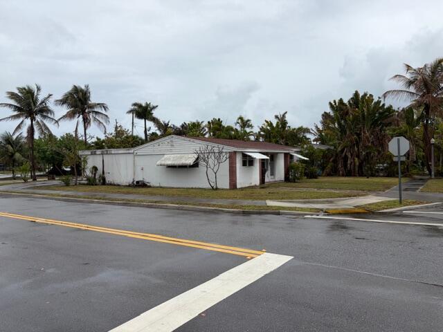 A single-story white house with a brown roof sits on a corner lot with palm trees — 1029 Ardmore Road, West Palm Beach FL 33401, WEST PALM BEACH, FL