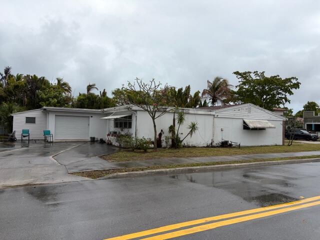 A single-story white house with a garage and a driveway under a cloudy sky — 1029 Ardmore Road, West Palm Beach FL 33401, WEST PALM BEACH, FL