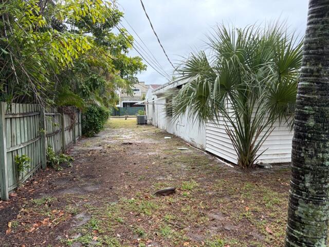 A narrow side yard features a wooden fence, a white house, and a palm tree — 1029 Ardmore Road, West Palm Beach FL 33401, WEST PALM BEACH, FL