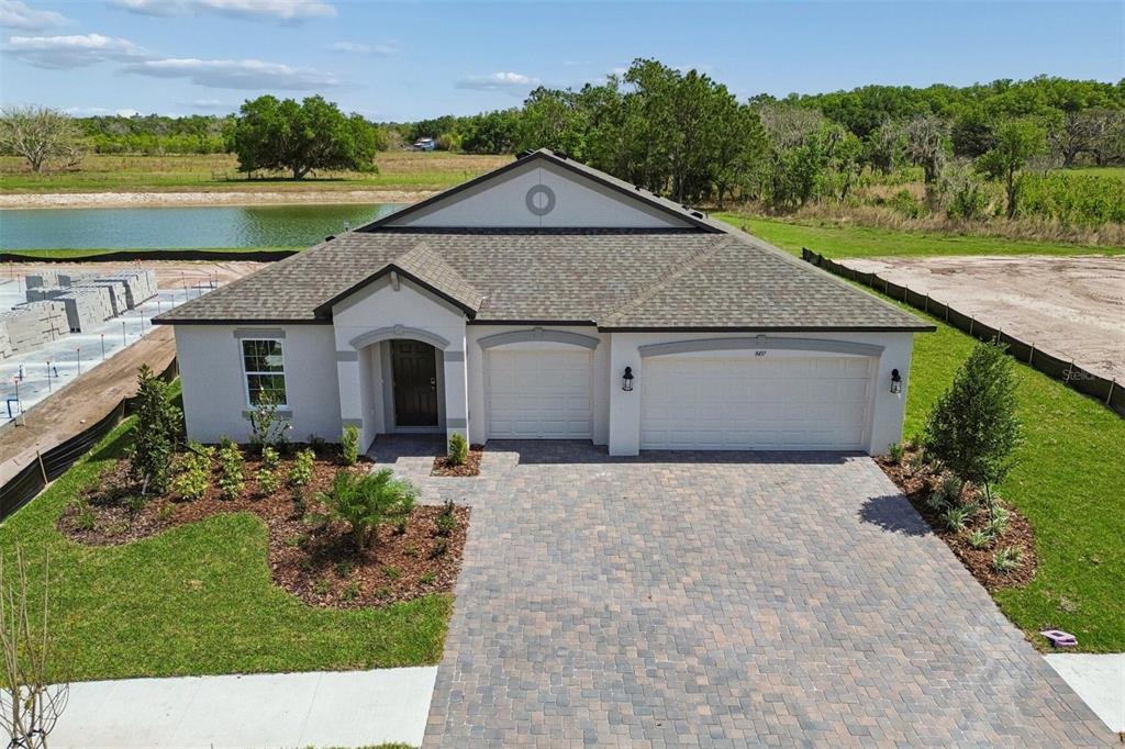 An exterior view of a single-story house with a paved driveway and a two-car garage — 8437 FOX DEN COVE, LAKELAND, FL
