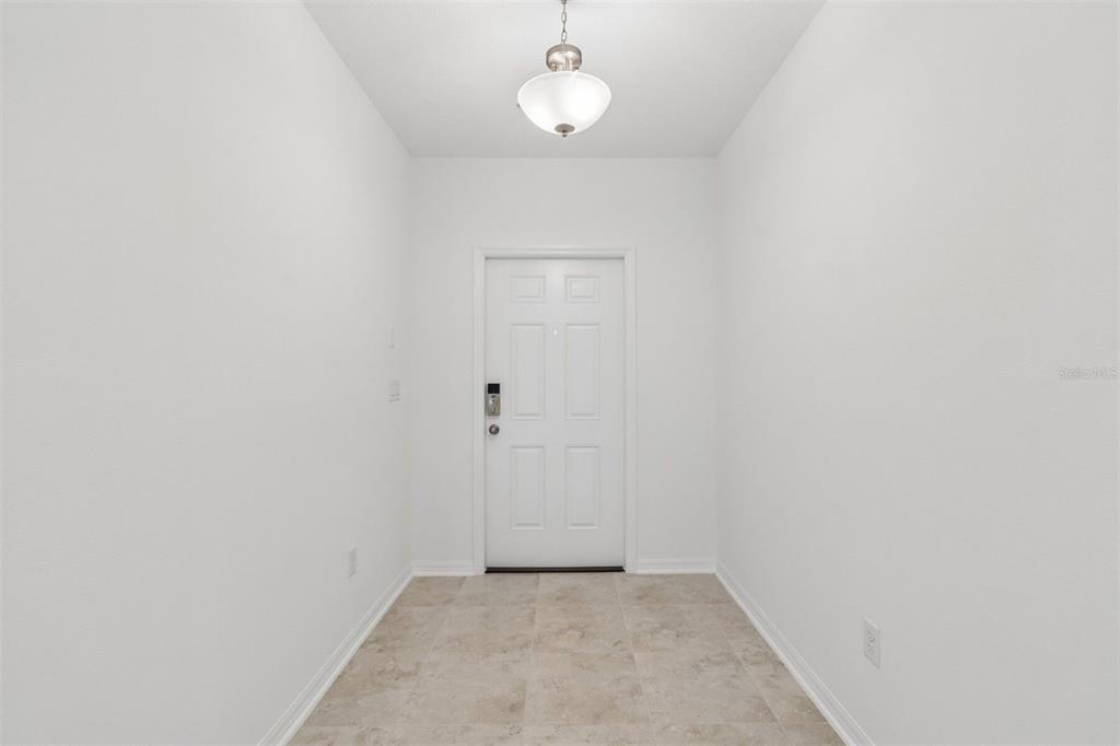 An entryway with white walls, a tiled floor, and a white front door — 8437 FOX DEN COVE, LAKELAND, FL