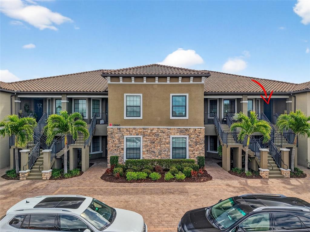 A two-story apartment building features a stone facade, stucco walls, and exterior staircases — 12660 SORRENTO WAY UNIT 204, BRADENTON, FL