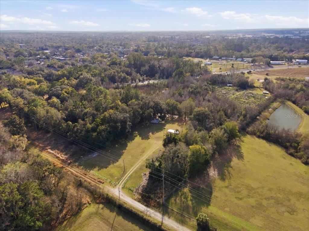 An aerial view shows a rural property with a small structure, trees, and open fields — 2400 SW 23RD TERRACE, GAINESVILLE, FL