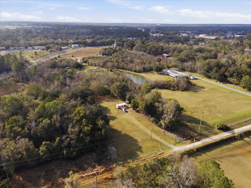 An aerial view shows a small house on a large, grassy, wooded lot — 2400 SW 23RD TERRACE, GAINESVILLE, FL