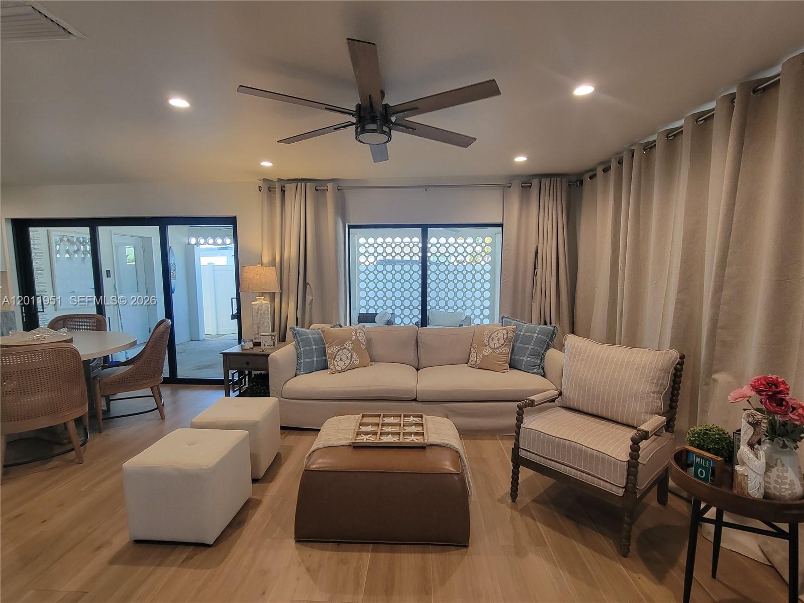A living room features a beige sofa, leather ottoman, striped armchair, and light wood flooring — 11339 5th Avenue Ocean, Marathon FL 33050, MARATHON, FL