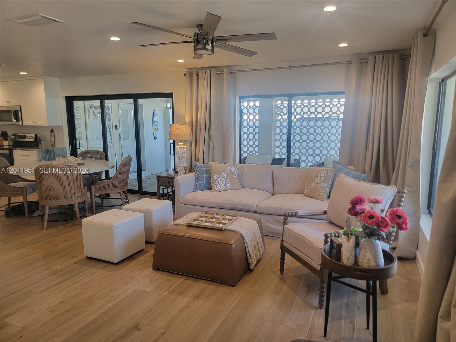 A living room features a sectional sofa, leather ottoman, dining area, and sliding glass doors — 11339 5th Avenue Ocean, Marathon FL 33050, MARATHON, FL