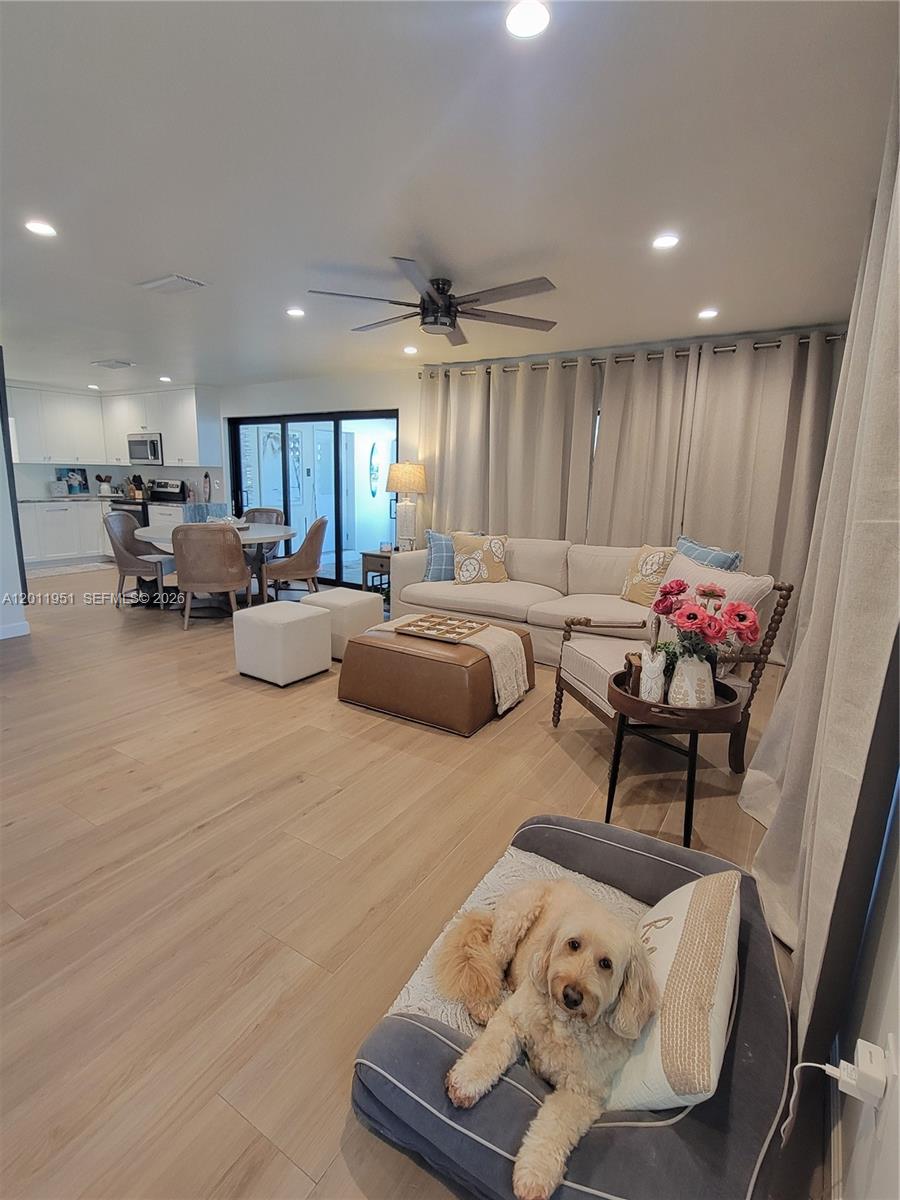A living room with light wood floors, a sectional sofa, and an open kitchen area — 11339 5th Avenue Ocean, Marathon FL 33050, MARATHON, FL