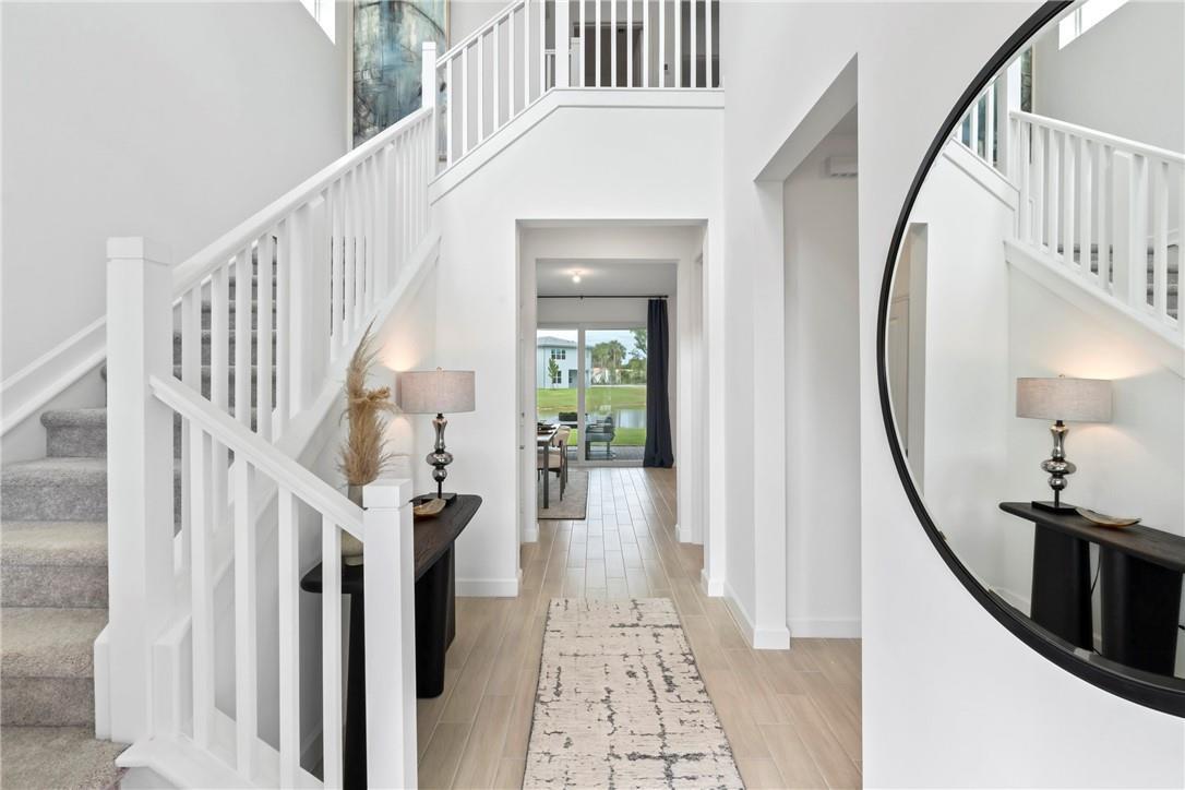 A bright foyer features a white staircase, a console table, and a view of a lake — 22812 Caciano Road, Boca Raton FL 33433, BOCA RATON, FL