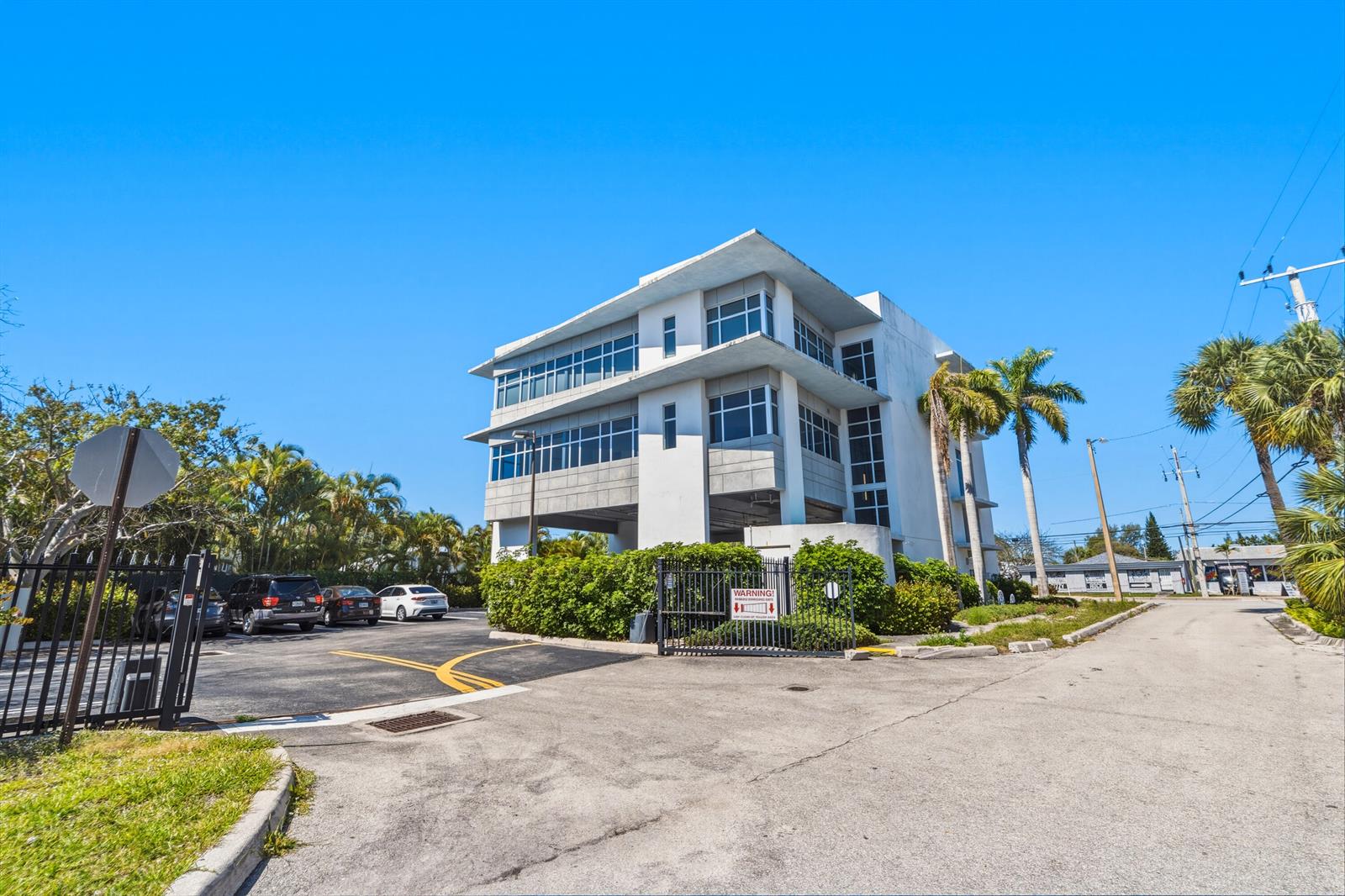 A three-story commercial building with a parking lot and gated entrance under a clear sky — 3330 N Federal Highway, Boynton Beach FL 33435, BOYNTON BEACH, FL