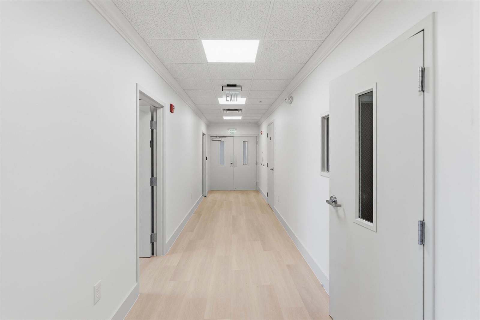 A bright, white hallway features light wood-look flooring, multiple doors, and recessed ceiling lights — 3330 N Federal Highway, Boynton Beach FL 33435, BOYNTON BEACH, FL