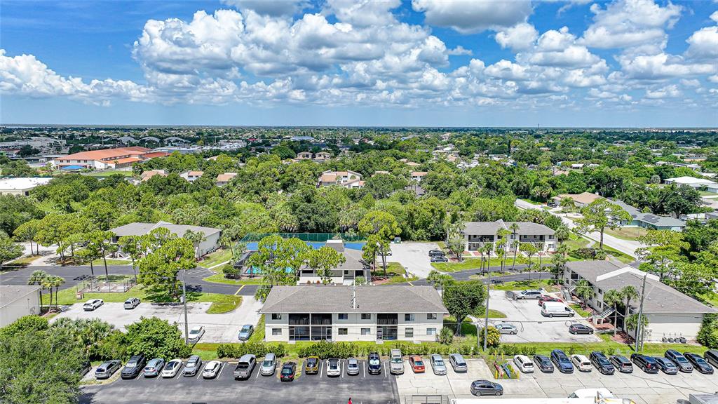 An aerial view shows several multi-story apartment buildings surrounded by parking lots and lush greenery — 22523 WESTCHESTER BOULEVARD UNIT E203, PORT CHARLOTTE, FL