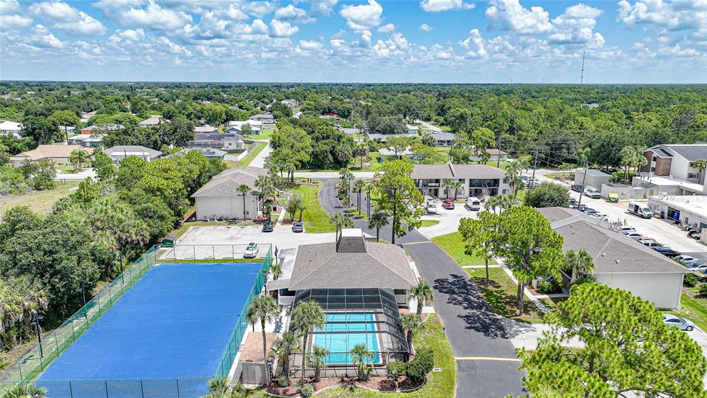 An aerial view shows a residential complex with a tennis court, swimming pool, and parking — 22523 WESTCHESTER BOULEVARD UNIT E203, PORT CHARLOTTE, FL