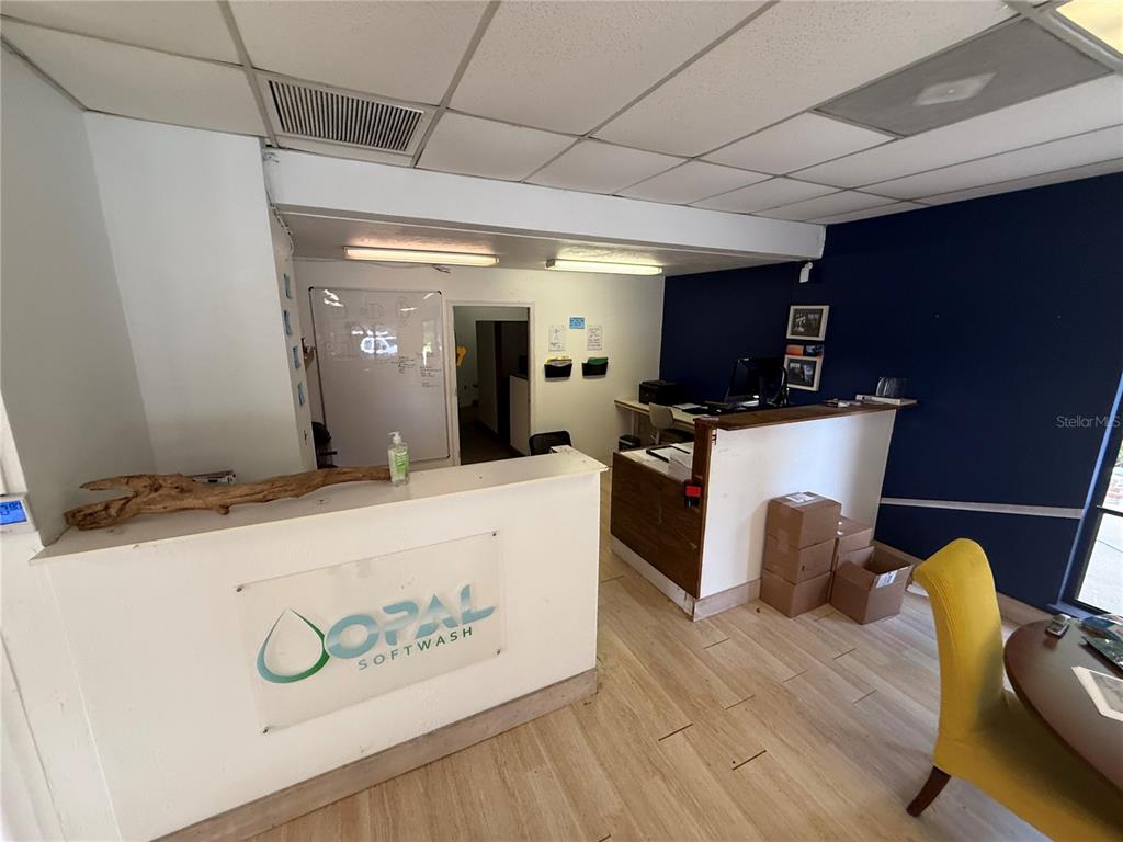 An office interior features a reception desk with a company logo and wood-look flooring — 3714 NW 97TH BOULEVARD, GAINESVILLE, FL