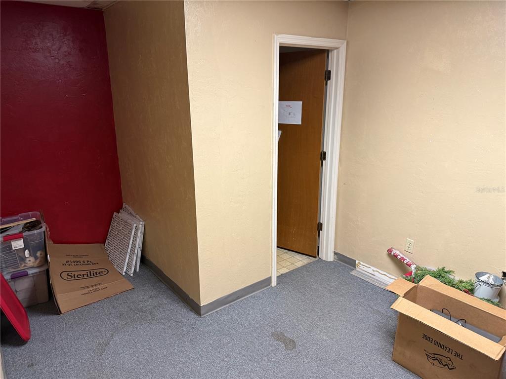 A room with red and beige walls, gray carpeting, and a doorway leading elsewhere — 3714 NW 97TH BOULEVARD, GAINESVILLE, FL
