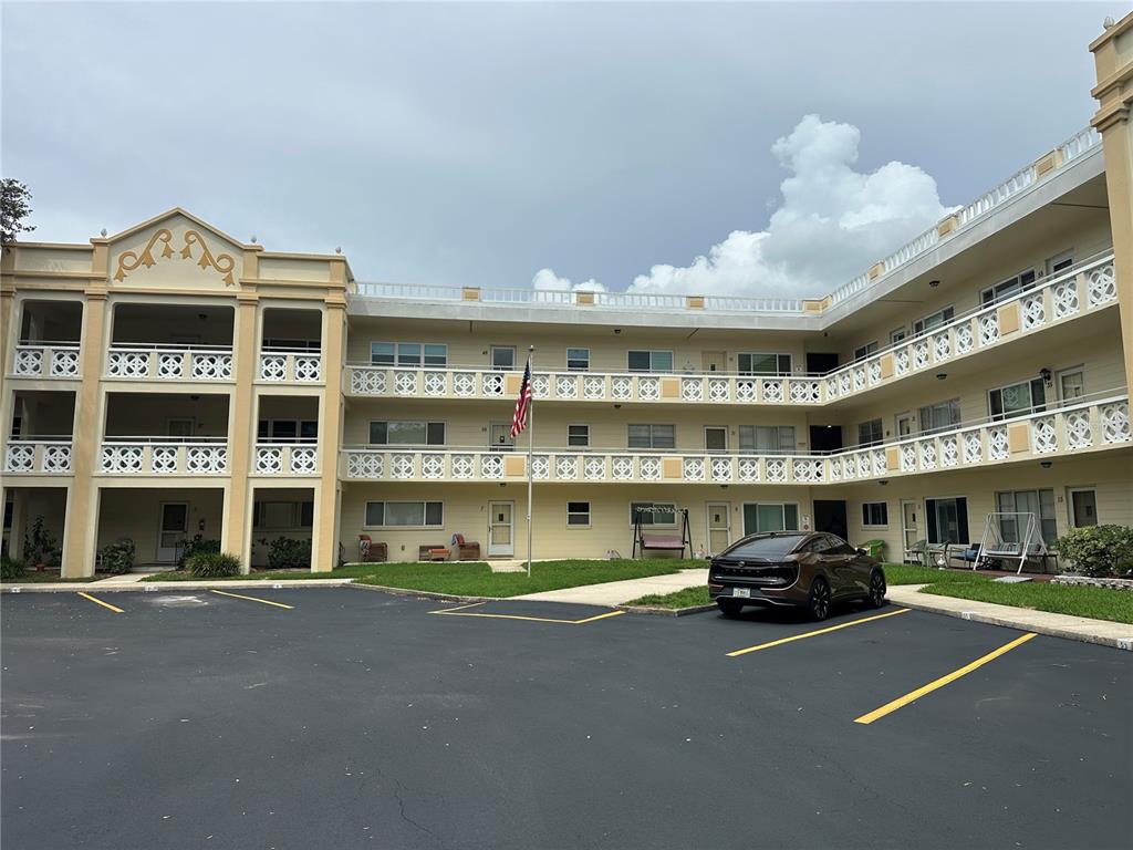 A three-story apartment building with a parking lot and an American flag in front — 2285 ISRAELI DRIVE UNIT 29, CLEARWATER, FL