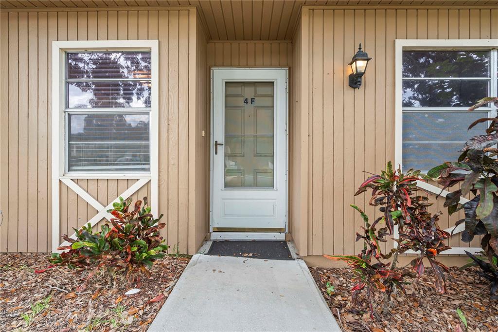The exterior of a tan building features a white front door labeled 4 F — 11511 113TH STREET UNIT 4F, LARGO, FL