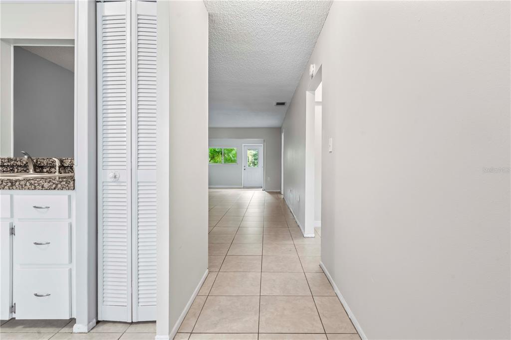 A hallway with tile flooring leads from a kitchen toward an exterior door — 11511 113TH STREET UNIT 4F, LARGO, FL