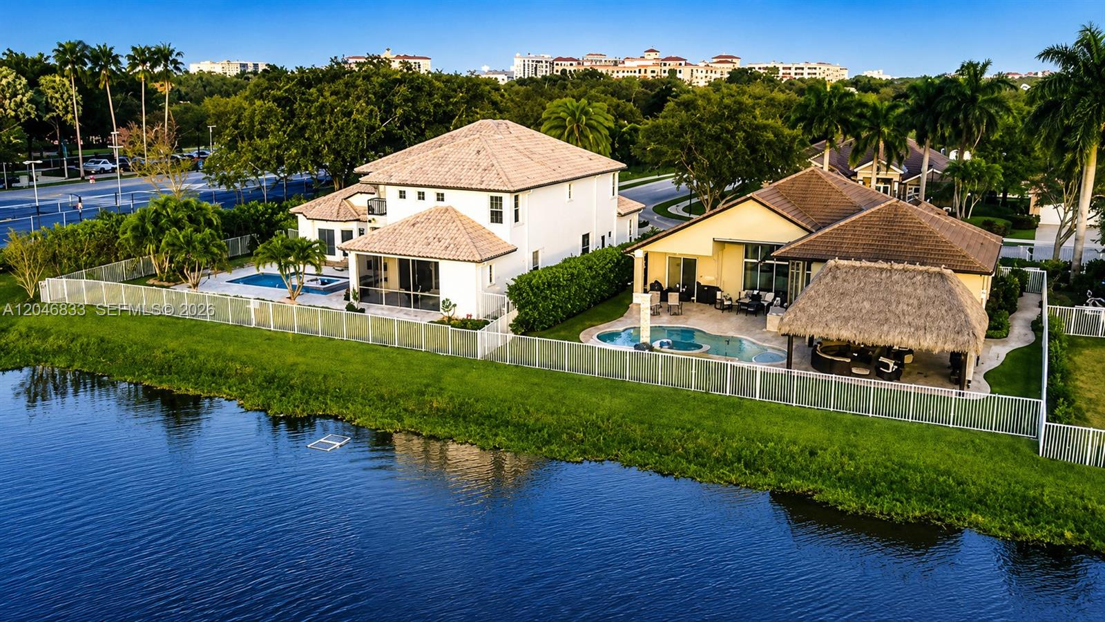 An aerial view shows two houses with swimming pools and a thatched-roof patio by water — 3683 W Lakes Estates Dr, Davie FL 33328, DAVIE, FL