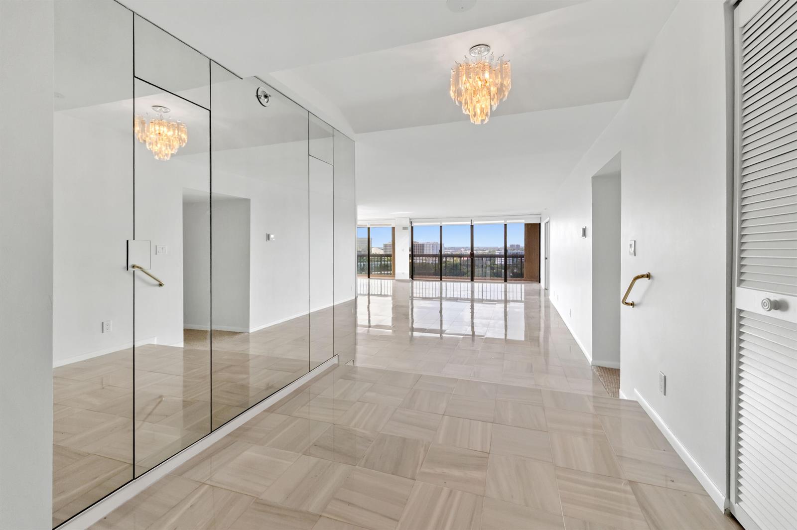 A bright hallway with mirrored walls, tile flooring, and a view of the city skyline — 1900 Consulate Place # 1004, West Palm Beach FL 33401, WEST PALM BEACH, FL