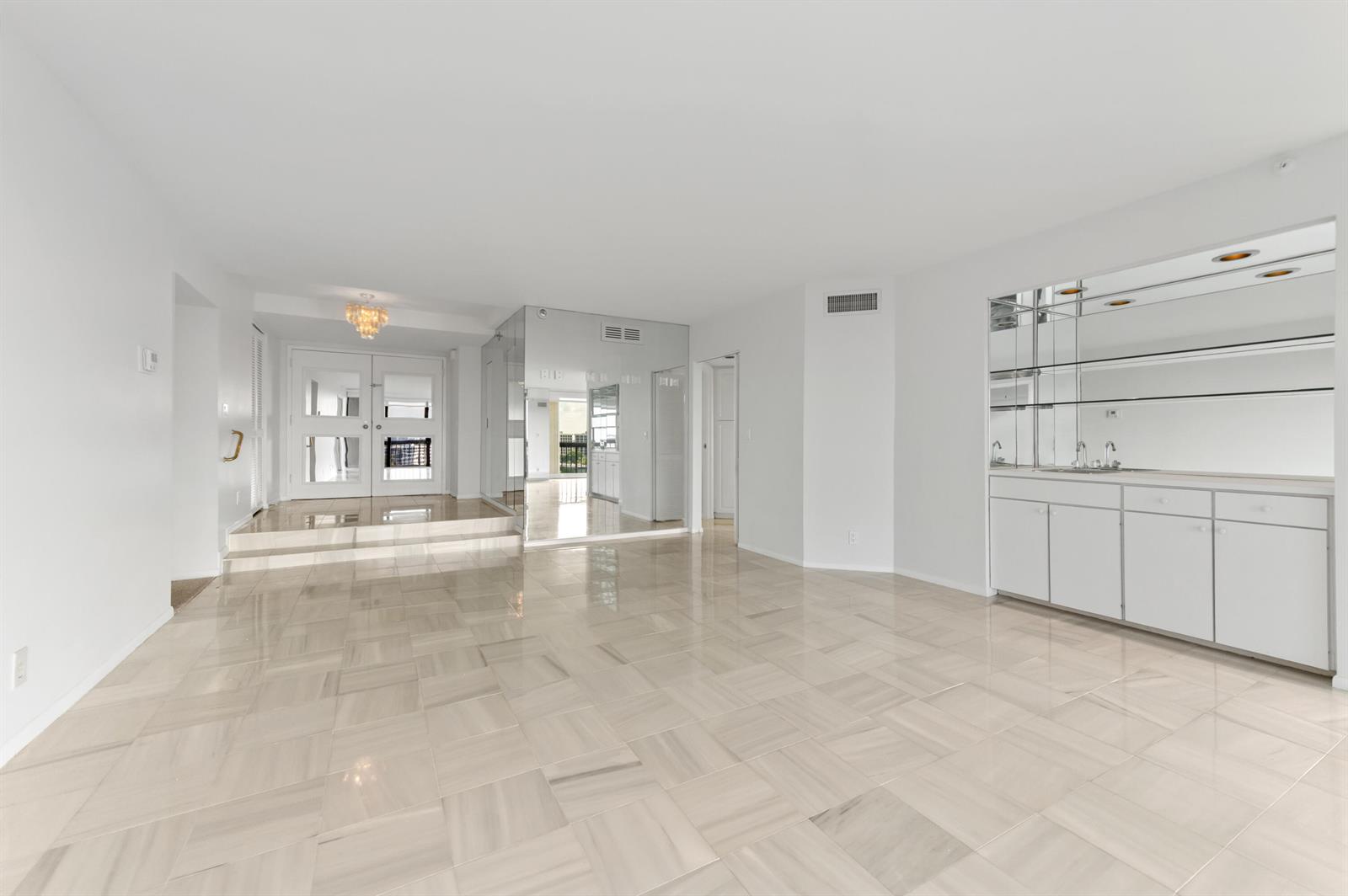 A bright, open living area features white tile floors, a wet bar, and mirrored walls — 1900 Consulate Place # 1004, West Palm Beach FL 33401, WEST PALM BEACH, FL