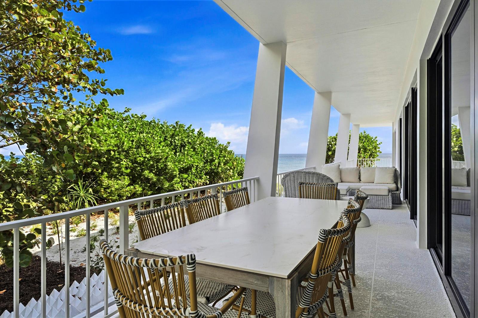 A covered outdoor balcony features a dining table, wicker chairs, and a view of the ocean — 2275 S Ocean Boulevard # 207n, Palm Beach FL 33480, PALM BEACH, FL