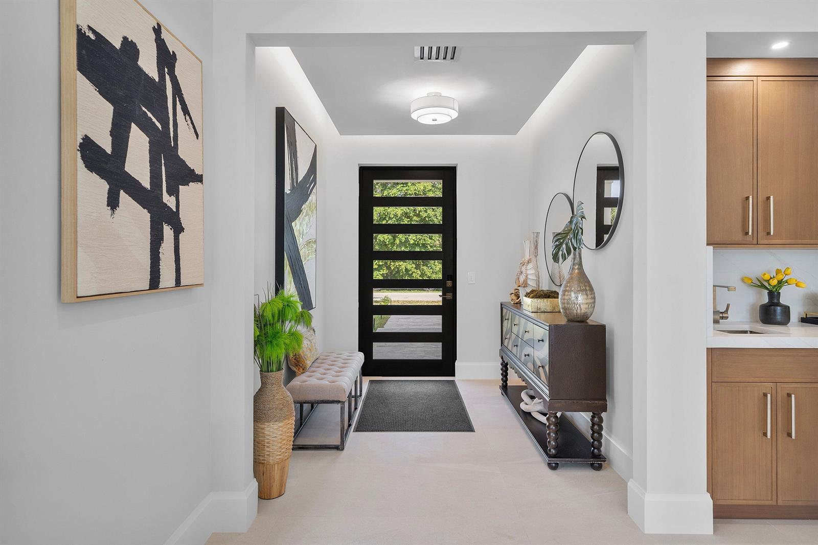 A modern entryway features a black front door, a console table, and a tufted bench — 731 SE 4th Avenue, Delray Beach FL 33483, DELRAY BEACH, FL