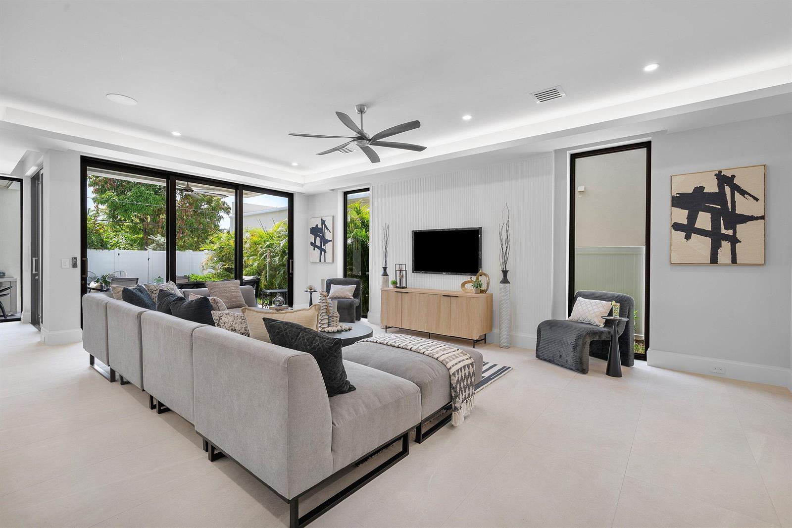 A modern living room features a large gray sectional, a media console, and floor-to-ceiling windows — 731 SE 4th Avenue, Delray Beach FL 33483, DELRAY BEACH, FL