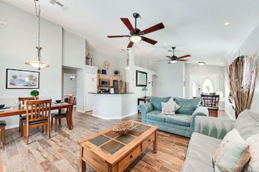 An open-concept living and dining area features wood-look tile flooring and two ceiling fans — 768 MAJESTY DRIVE, DAVENPORT, FL