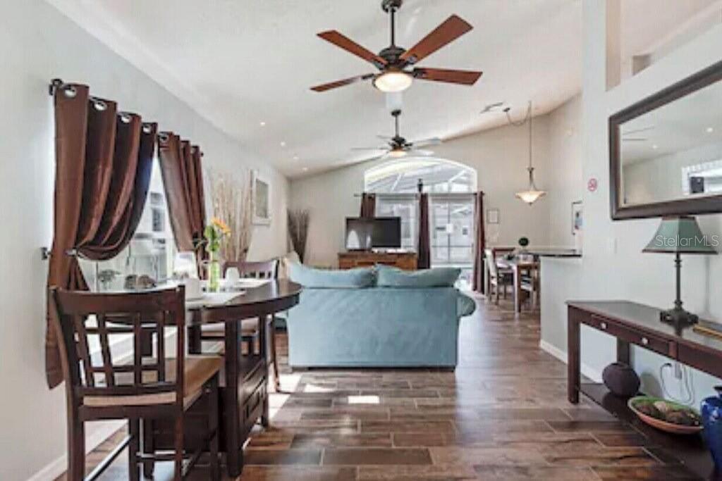 A living and dining area with wood-look tile floors, a blue sofa, and ceiling fans — 768 MAJESTY DRIVE, DAVENPORT, FL