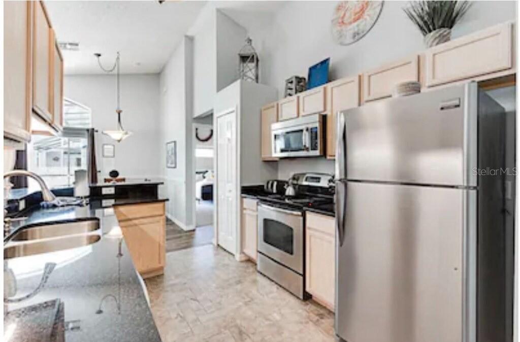 A kitchen features light wood cabinets, stainless steel appliances, and dark granite countertops — 768 MAJESTY DRIVE, DAVENPORT, FL