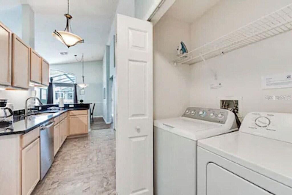 A laundry closet with a washer and dryer sits adjacent to a modern kitchen — 768 MAJESTY DRIVE, DAVENPORT, FL