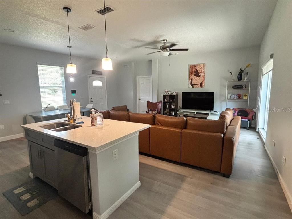 An open-concept kitchen with a central island overlooks a living room with a leather sectional — 1313 5TH STREET, ORANGE CITY, FL