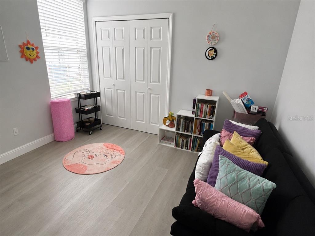 A room with light wood-look flooring, a black sofa, a bookshelf, and a closet — 1313 5TH STREET, ORANGE CITY, FL