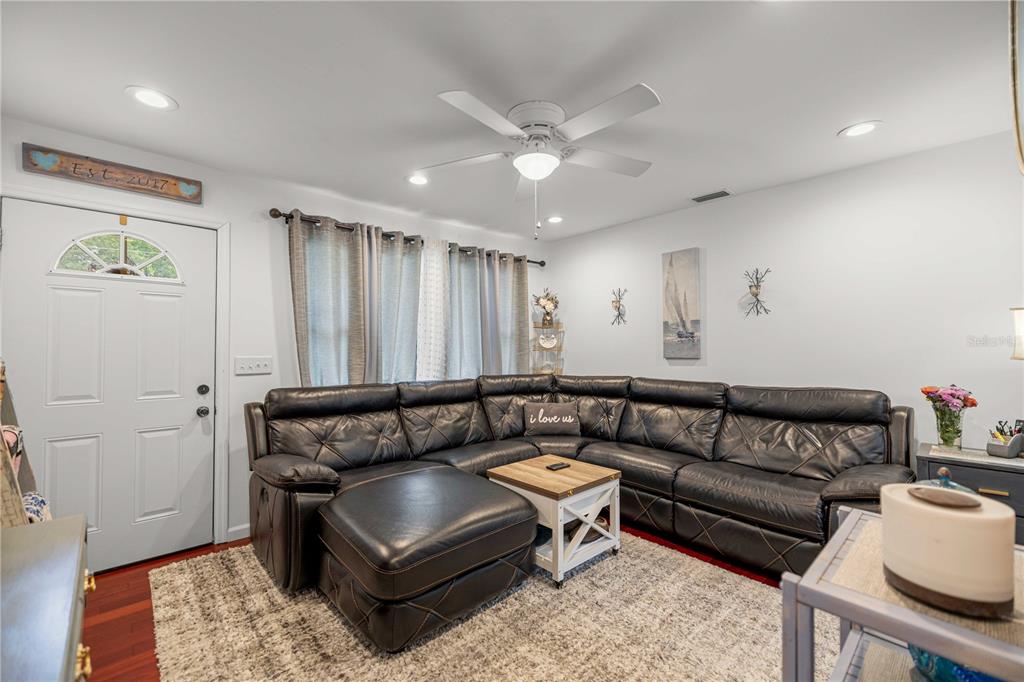 A living room features a large black sectional sofa, a white coffee table, and curtains — 1512 NE 37TH STREET, OCALA, FL