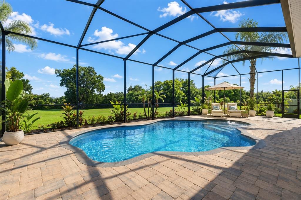 A swimming pool with a screened enclosure sits on a paved patio overlooking a grassy yard — 1310 LOREA LANE, BRANDON, FL