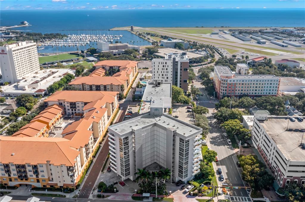 An aerial view shows a multi-story apartment building surrounded by urban infrastructure and a harbor — 470 3RD STREET S UNIT 515, ST PETERSBURG, FL