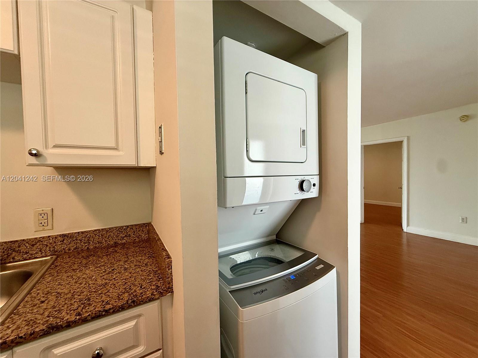 A stacked Whirlpool washer and dryer unit is installed in a kitchen alcove — 7800 Collins Ave # 407, Miami Beach FL 33141, MIAMI BEACH, FL