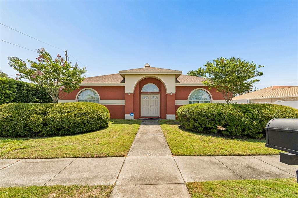 A single-story house with a terracotta-colored exterior, arched windows, and a central double-door entrance — 7791 CARVER COURT, SEMINOLE, FL