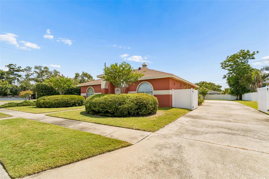 A single-story house with a red exterior, arched windows, and a large concrete driveway — 7791 CARVER COURT, SEMINOLE, FL