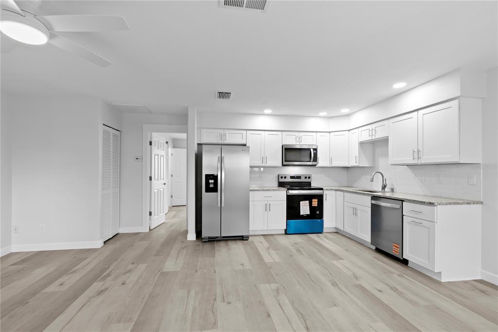 A kitchen with white cabinets, stainless steel appliances, and light wood-look flooring — 6225 ELMHURST DRIVE, NEW PORT RICHEY, FL