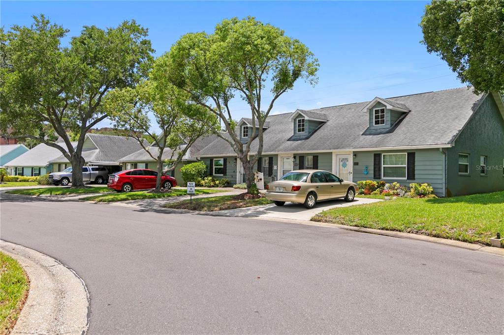 A row of single-story houses with gray siding and dormer windows sits along a street — 6225 ELMHURST DRIVE, NEW PORT RICHEY, FL