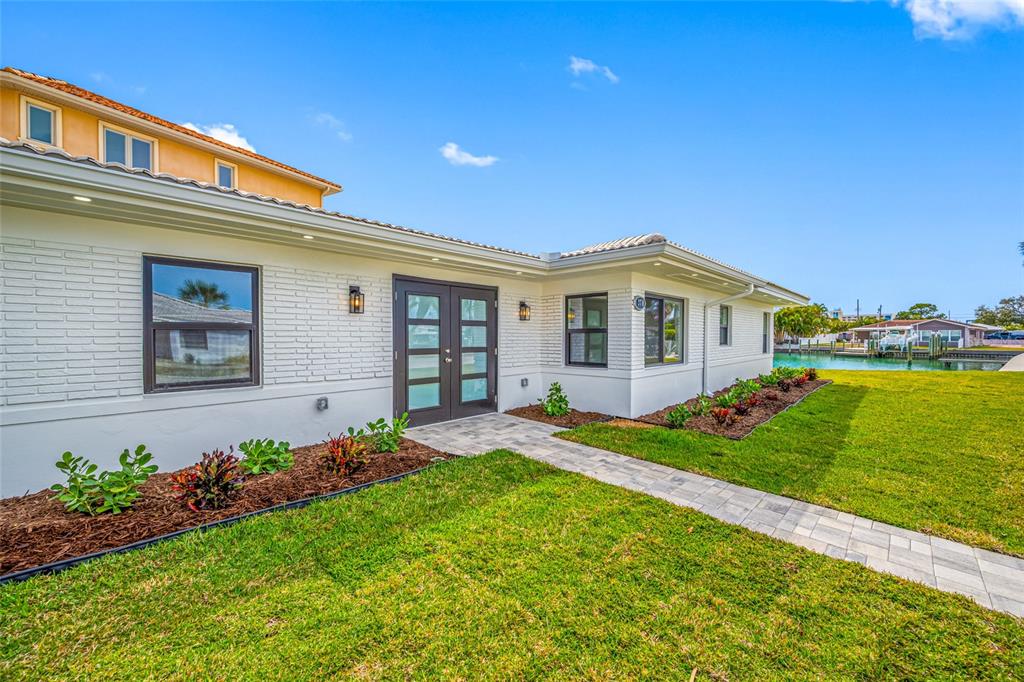 A white brick house exterior features a paved walkway leading to dark double doors — 370 59TH AVENUE, ST PETE BEACH, FL